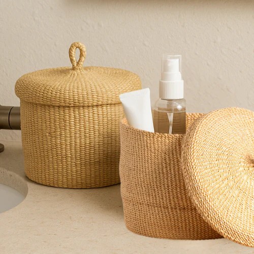 Handwoven African Banasco basket in a natural color, holding bathroom essentials on a bathroom counter