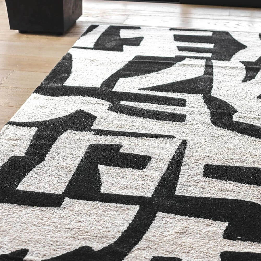 A soft white rug with black geometric patterns