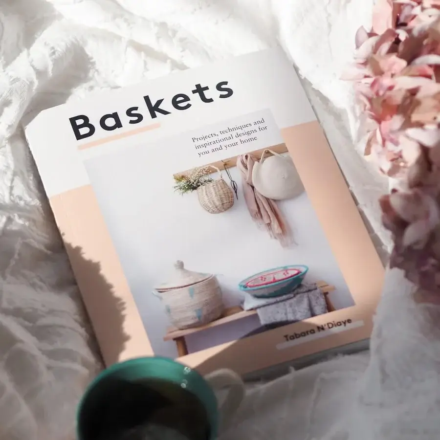 Book on DIY basket weaving placed on a bed next to a coffee mug