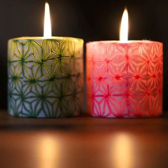 Lit candles with green and pink geometric patterns