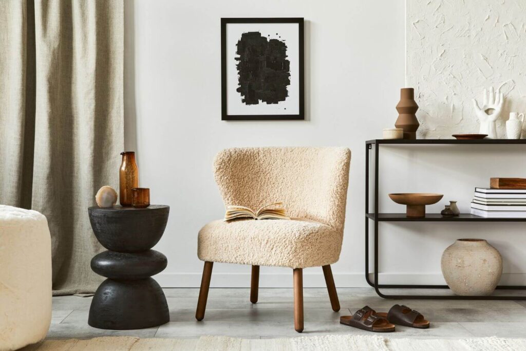 African Interior Design Styles Chic African-inspired seating area with a cream chair upholstered in wool-like material, organic elements such as the dark wooden side-table, brown vase and a contemporary black and white painting on the wall