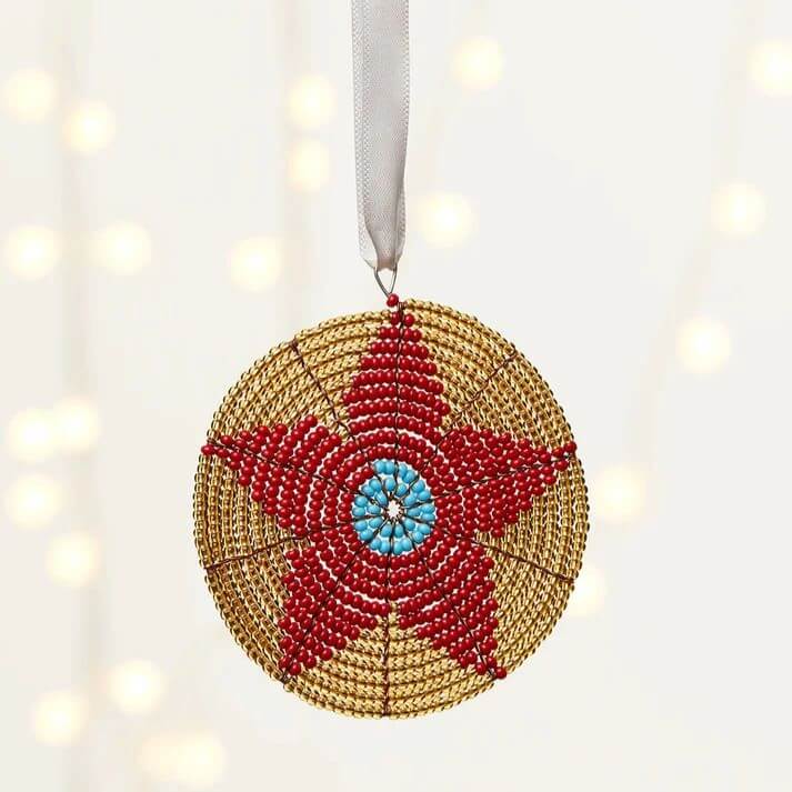 African Christmas decoration: woven ornament, red flower on a sand background