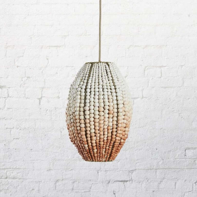 Oval-shaped pendant light made out of clay beads with a color gradient from white to coral