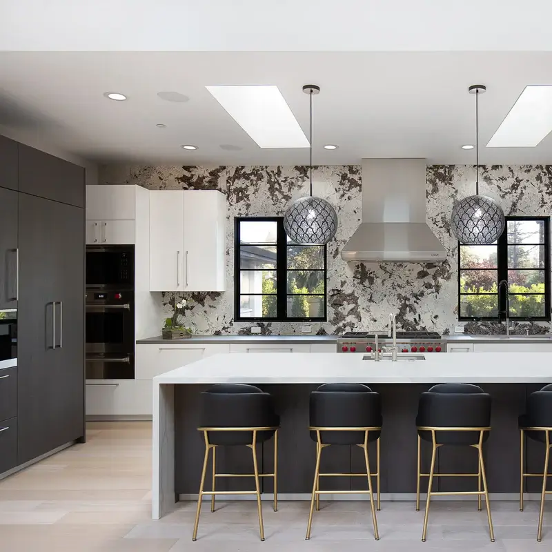 A modern kitchen with a large island in the middle and 2 black brass pendant lights above it. Unique pendant lights handmade in Morocco.