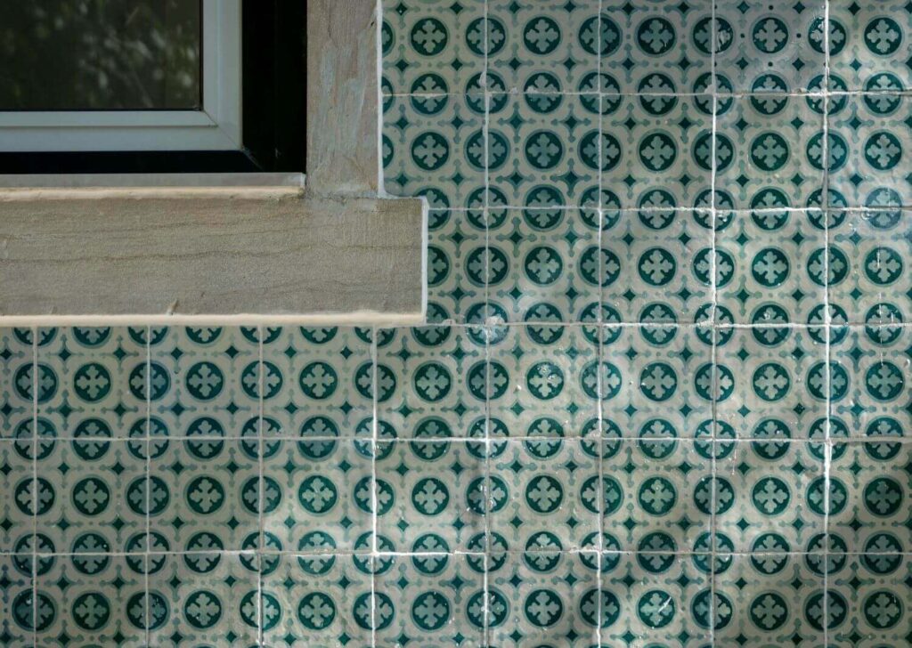 Window corner with a wall tiled with beautiful Moroccan cement tiles in blue-green