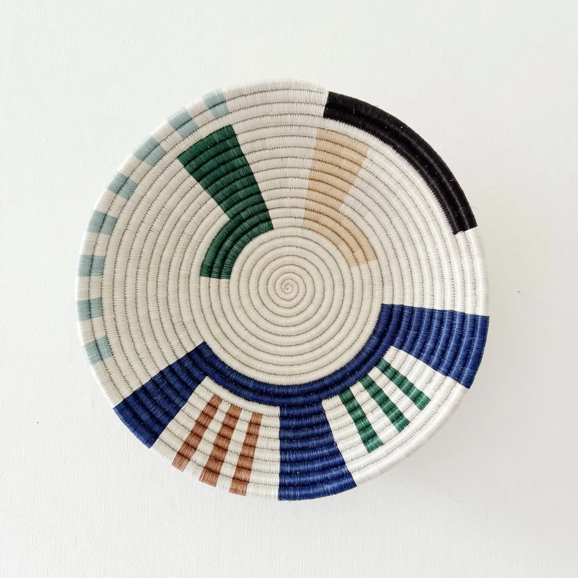A white woven wall basket with joyful blue, green and beige geopmetric patterns