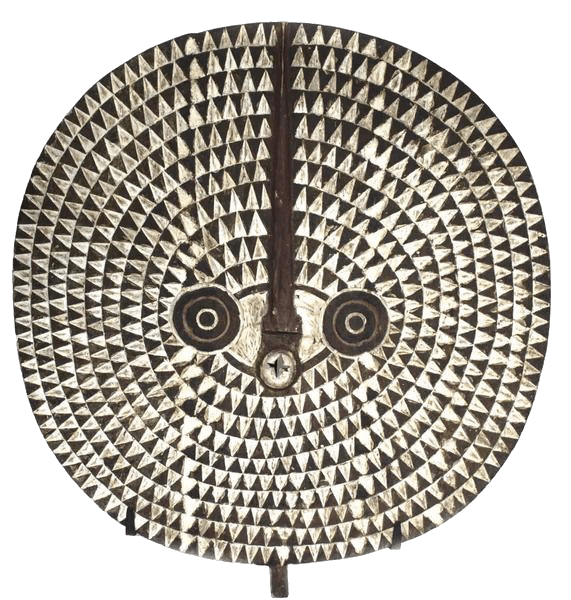 A round, flat mask with geometric designs, possibly of African or tribal origin. Concentric rings of small, evenly spaced triangles radiate outward from the center, alternating in color to create a dynamic pattern. In the central area of the mask, simplified facial features composed of circles and lines are visible, suggesting eyes and a nose. The mask is divided vertically bisecting the nose. The overall impression is one of craftsmanship and cultural significance.
