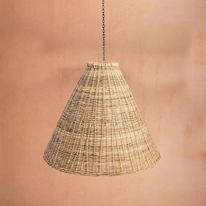 Wicker pendant light hanging against a textured peach backdrop.