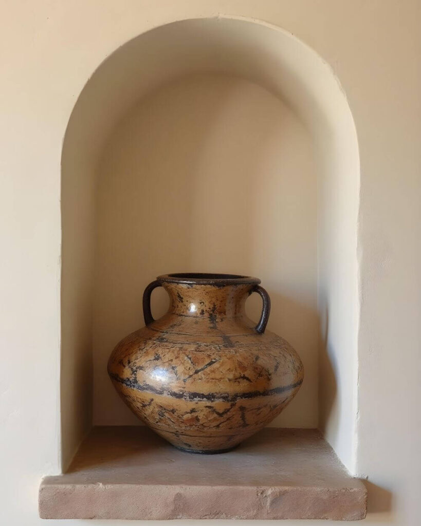 Earthenware African pottery vase with handles, displayed in an arched alcove.
