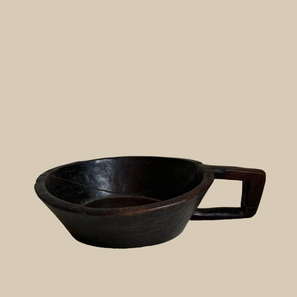 Close-up of a handcrafted dark wooden African bowl with a unique handle.