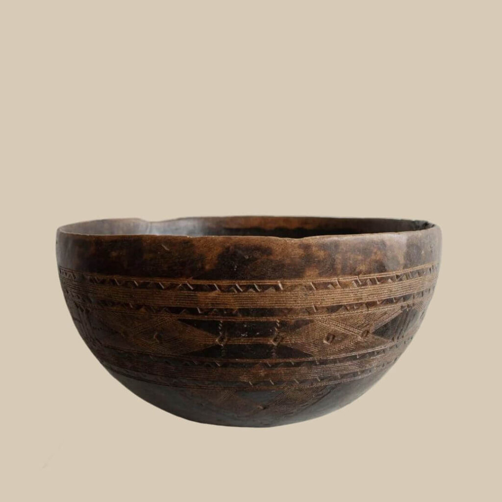 Close-up of a hand-carved African bowl with geometric patterns, showcasing the craftsmanship and cultural significance.