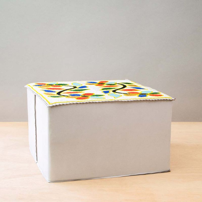 White leather Yoruba pouffe with colorful beaded floral motifs on the top side