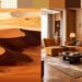 A split image showing desert dunes on the left, with warm, earthy tones of sand and shadow, and a stylish living room on the right, featuring a brown and amber color scheme as an example of earthy color palettes. Modern furniture, and soft lighting, evoking a cozy, elegant atmosphere.