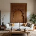 A bright, modern living room featuring a large white sofa centered in front of an oversized, light wood headboard or wall panel with carved Moroccan art in the shape of a grand horseshoe arch. The room includes a large patterned textile hanging on the left, a natural fiber rug, and a wood coffee table with decorative ceramic vases.