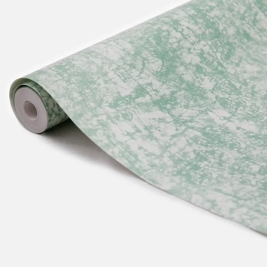 A green wallpaper roll on the floor, with motifs inspired by Adire fabric from Nigeria